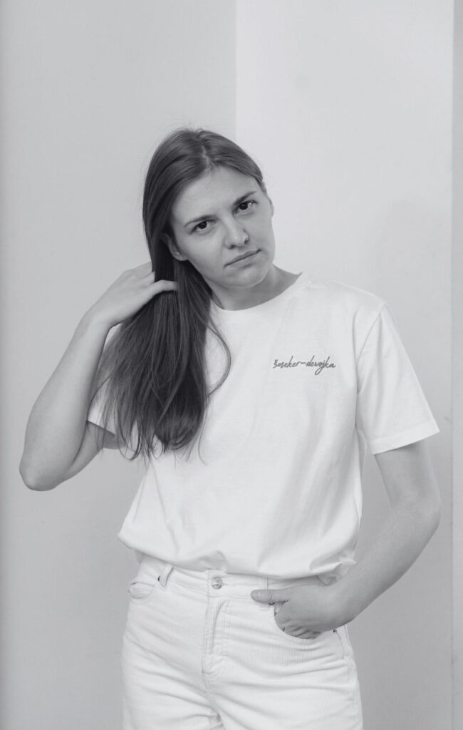 is) A black-and-white portrait of Radmila Petrović in front of a white wall. Een zwart-witportret van Radmila Petrović voor een witte muur.
