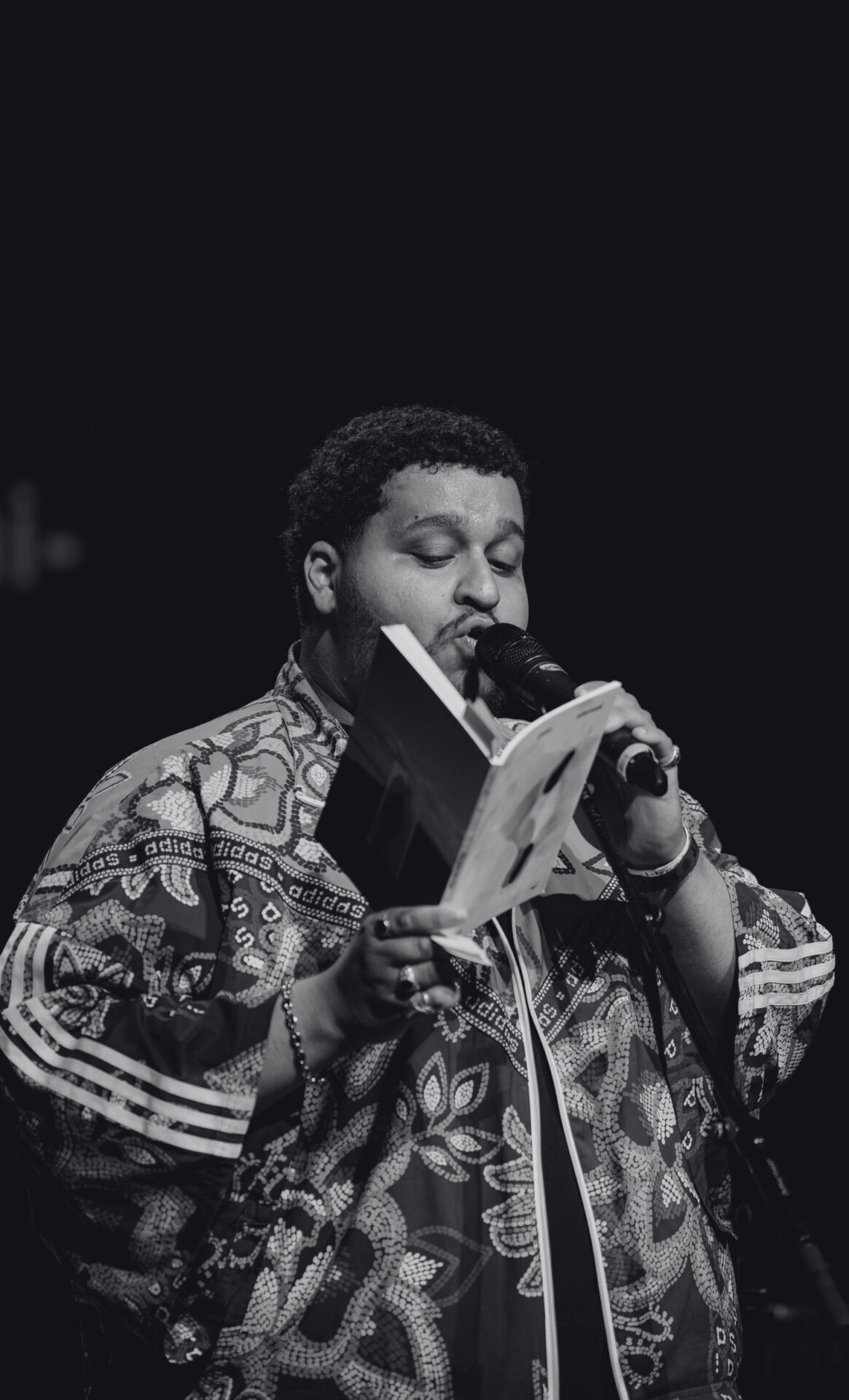 A black-and-white photo of Benzokarim reciting a poem.Een zwart-witfoto van Benzokarim, terwijl die een gedicht voordraagt.