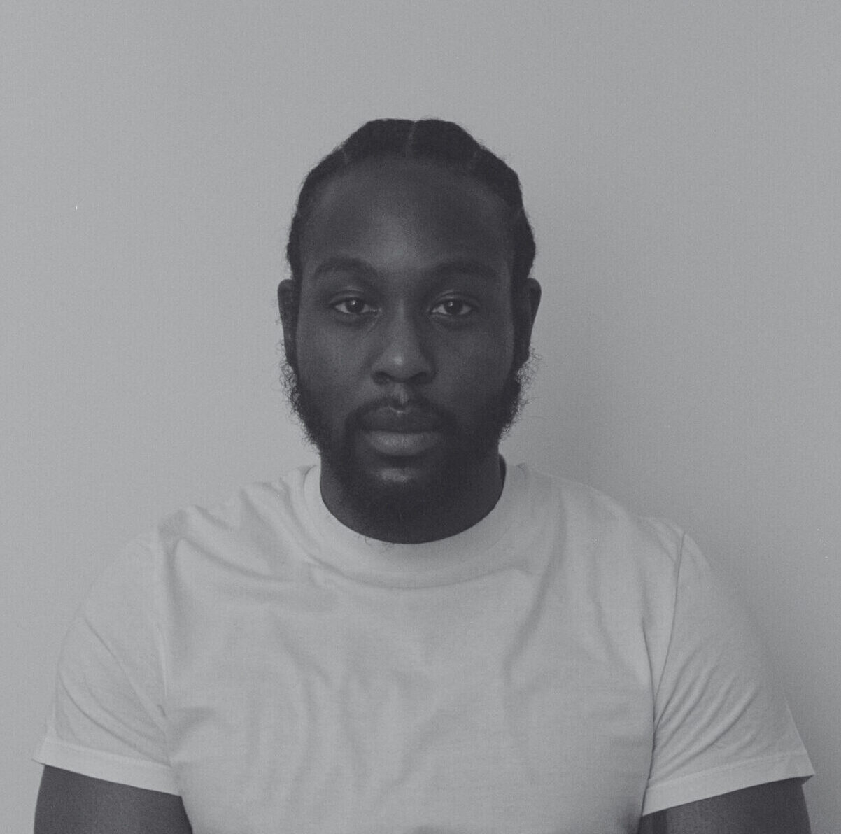 A black-and-white portrait of Caleb Femi looking in the camera. Een zwart-witportret van Caleb Femi die naar de camera kijkt.