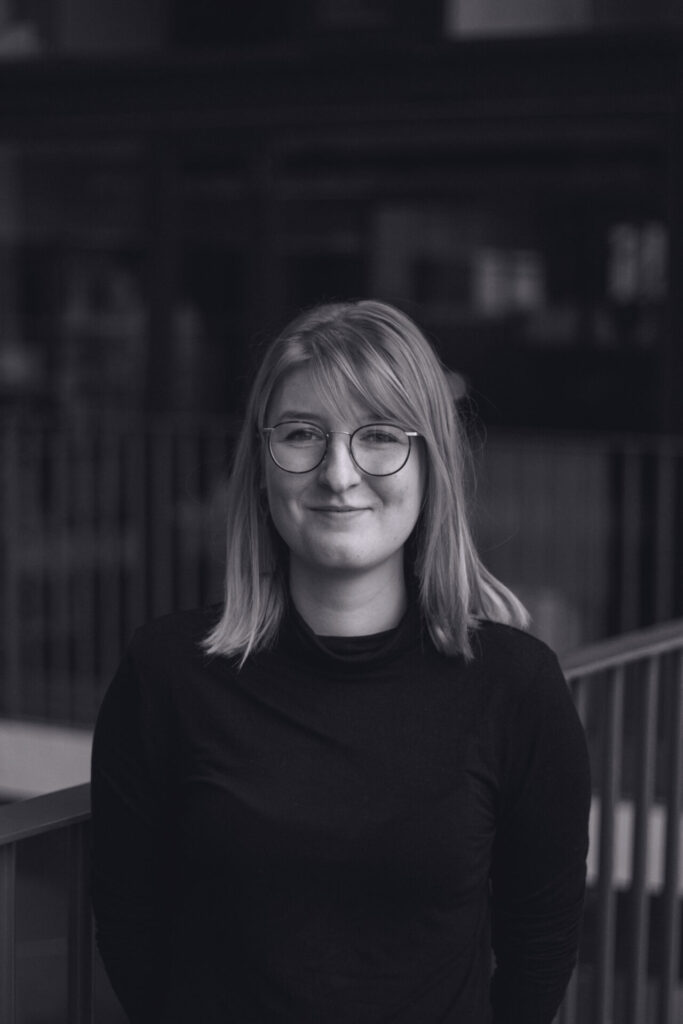 A black-and-white portrait of Eline van Leeuwen smiling at the camera. Een zwart-witportret van Eline van Leeuwen die naar de camera lacht.