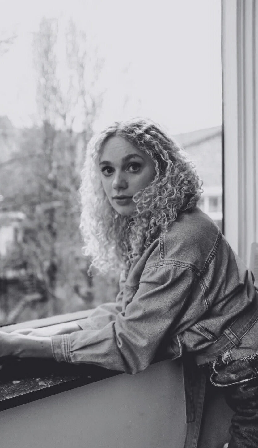 A black-and-white picture of Iduna Paalman standing in front of a window. Een zwart-witfoto van Iduna Paalman die voor een raam staat.