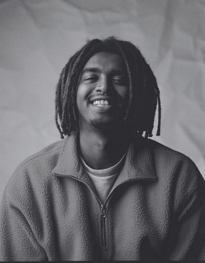 A black-and-white portrait of Mahat Arab smiling at the camera. Een zwart-witfoto van Mahat Arab die naar de camera lacht.