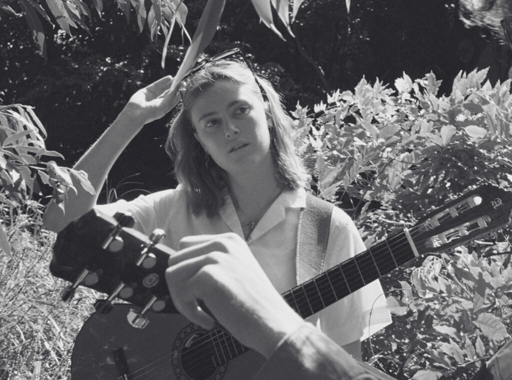 A black-and-white picture of Nadine Rypkema holding a guitar. Een zwart-witfoto van Nadine Rypkema die een gitaar vasthoudt.