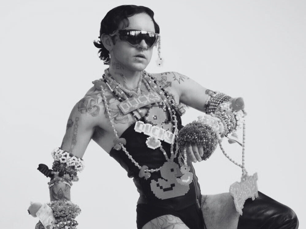 A black-and-white portrait of DJ DUCKY wearing a lot of jewelry. Een zwart-witportret van DJ DUCKY die veel sieraden draagt.