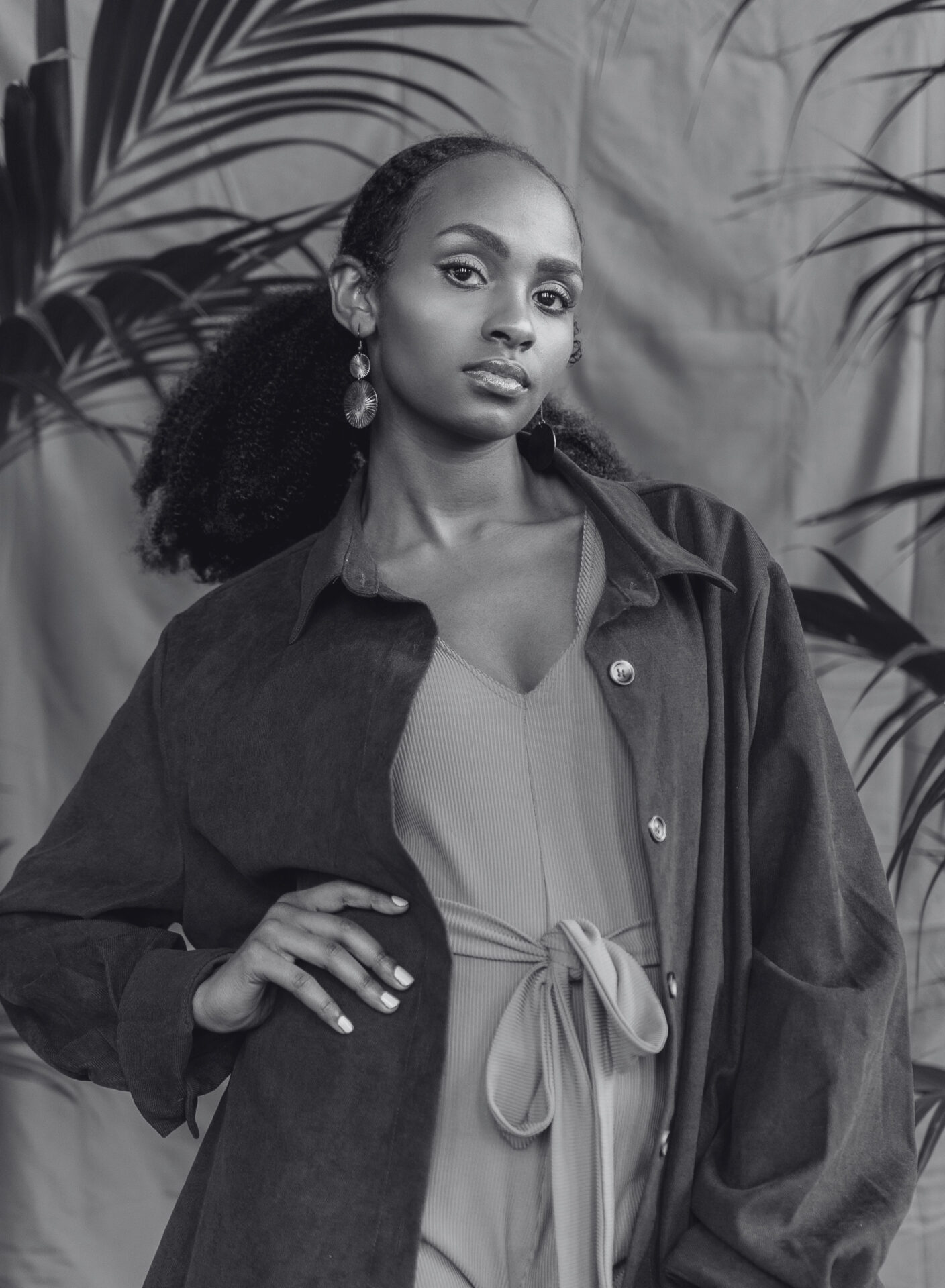 A black-and-white portrait of Kelly Bigirindavyi looking at the camera with one hand on their hip. Een zwart-witportret van Kelly Bigirindavyi, die in de camera kijkt met één hand op de heup.
