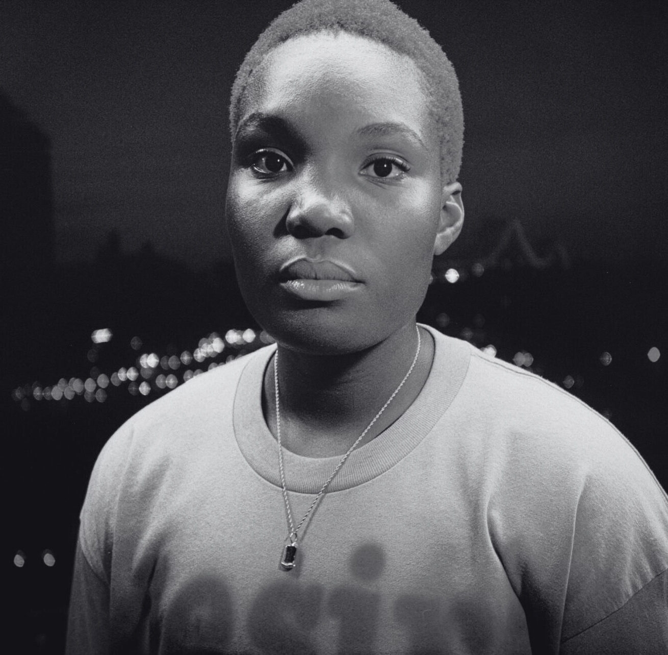 A black-and-white picture of Arlo Parks looking at the camera. Een zwart-witfoto van Arlo Parks die naar de camera kijkt.
