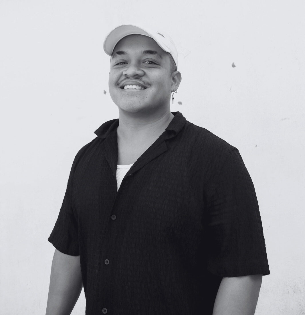 A black-and-white picture of Tyler Koudijzer smiling at the camera. Een zwart-witfoto van Tyler Koudijzer die naar de camera lacht.