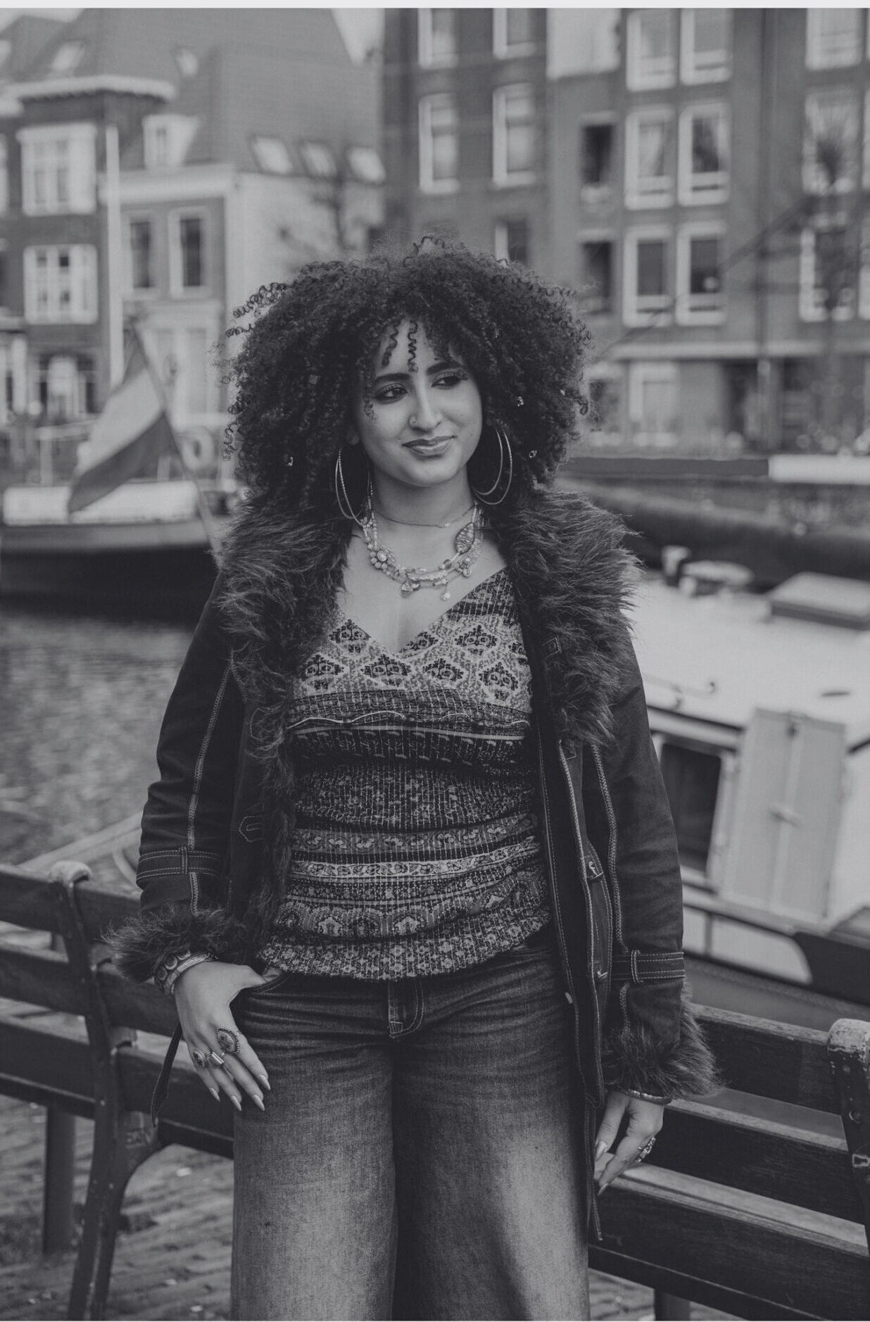 A black-and-white picture of Oumaima Yahiaoui standing in front of buildings. Een zwart-witfoto van Oumaima Yahiaoui die voor gebouwen staat.