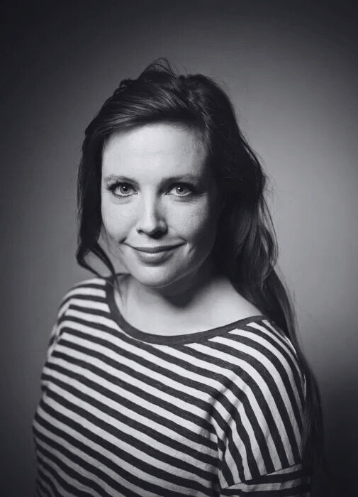 A black-and-white portrait of Ellen Deckwitz smiling at the camera. Een zwart-witportret van Ellen Deckwitz die naar de camera lacht.