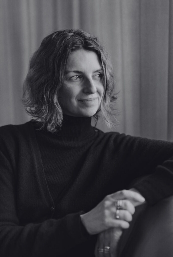 A black-and-white picture of Michelle Hutchison sitting and looking away from the camera. Een zwart-witfoto van Michelle Hutchison die zit en van de camera wegkijkt.