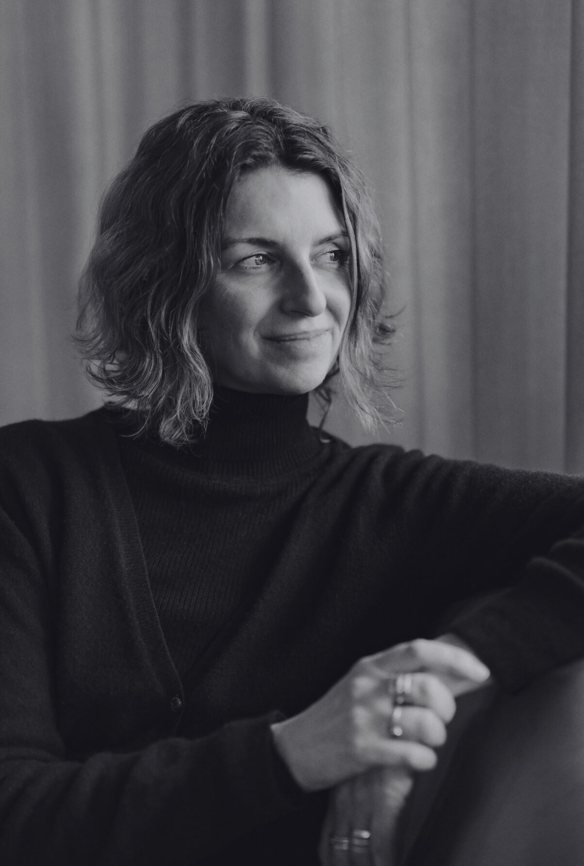 A black-and-white picture of Michelle Hutchison sitting and looking away from the camera. Een zwart-witfoto van Michelle Hutchison die zit en van de camera wegkijkt.